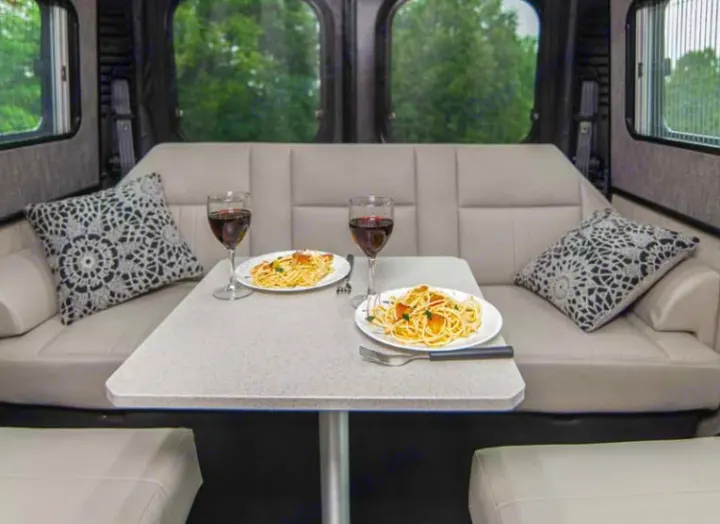 Enjoy a comfortable pasta and wine dinner in your RV rental. This cozy dinette is ideal for relaxing meals on the road.. Roadtrek Roadtrek Class B 2021