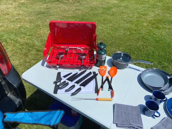 RV rental outdoor cooking setup with portable stove, kitchenware, knives, and pans on a table. Essential camping gear.. Dodge Grand Caravan 2008