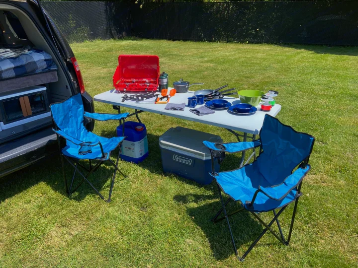 Car camping setup with a converted minivan, chairs, table, and cooking gear. Perfect for your next RV rental adventure!. Dodge Grand Caravan 2008