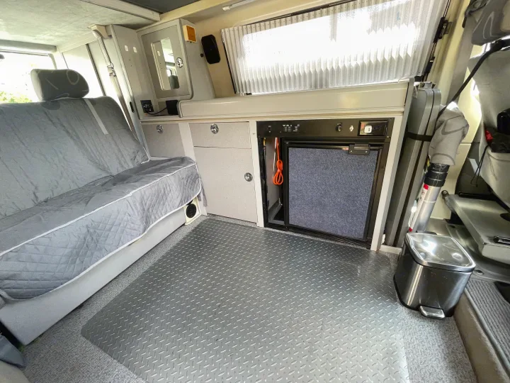 Inside this RV rental: bench seat, built-in fridge, cabinets, and durable diamond plate flooring for travel comfort.. Volkswagen Eurovan 1999
