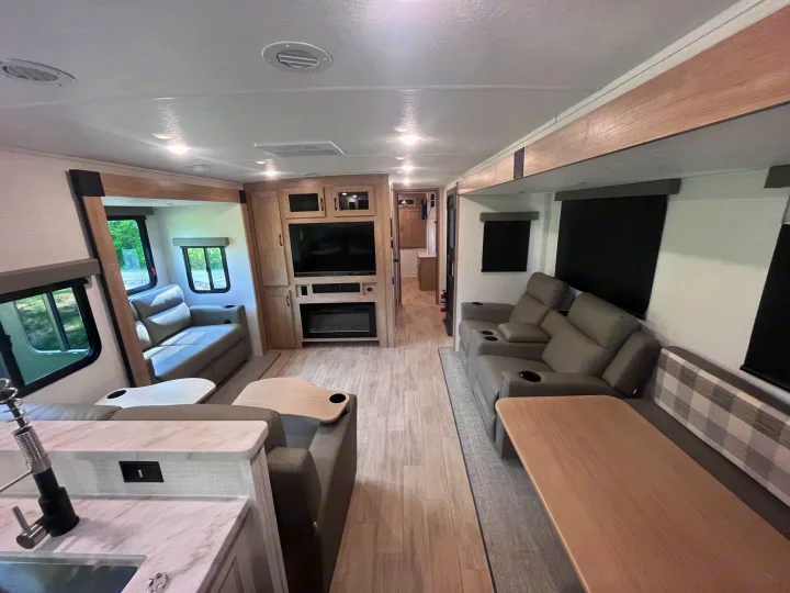 Spacious, modern RV rental interior featuring a comfortable living area, kitchen, and entertainment center.. Forest river 306RKTS Palomino 2025