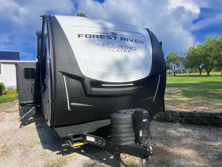 Front view of a sleek black and white Forest River Palomino Solaire travel trailer, ideal for your next RV rental getaway.. Forest river 306RKTS Palomino 2025