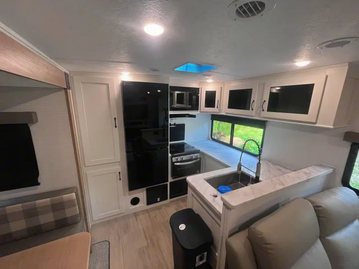 Experience this modern RV rental's interior: a bright space featuring a fully equipped kitchen, dining area, and comfy living seating.. Forest river 306RKTS Palomino 2025