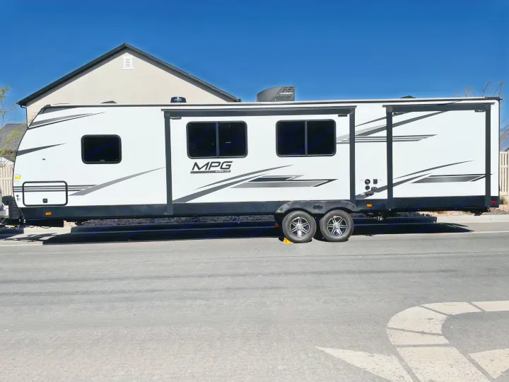 White travel trailer RV, possibly for rv rental, parked on asphalt with a house in background. Features "MPG ULTRA-LITE" graphics.. Other Other 2021