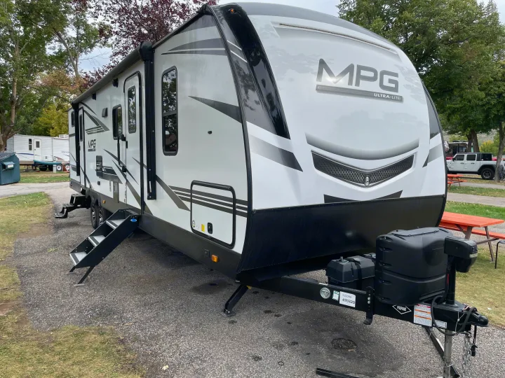 White MPG Ultra-Lite travel trailer (RV rental) parked at a campground, steps extended.. Other Other 2021