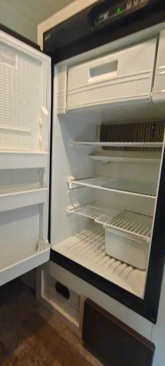 Clean, compact RV rental refrigerator, open to show empty shelves and top freezer, ready for travel adventures.. Forest River R-Pod 2023