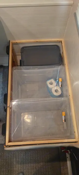 Maximized storage in an RV rental: Two clear bins hold essentials, including toilet paper, within a built-in wooden frame.. Forest River R-Pod 2023