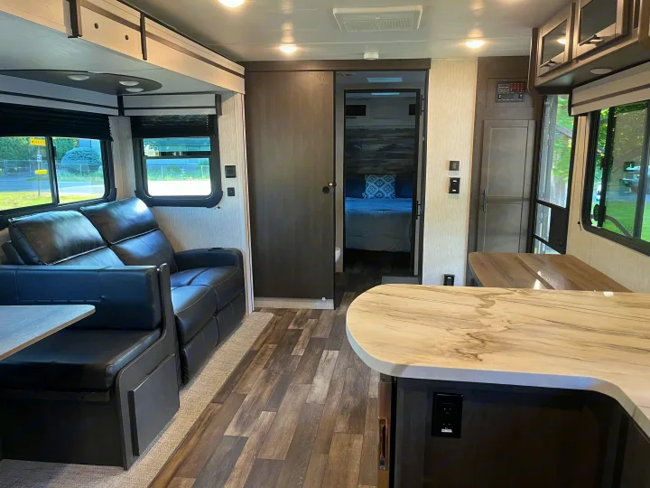 Spacious RV rental interior with black sofa, dining, kitchen island, and rear bedroom. Ready for your next adventure!. Crossroads RV Cruiser Aire 2022