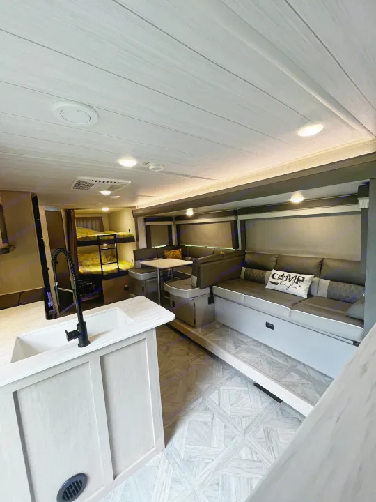 Spacious RV rental interior featuring a modern kitchen island, dinette, cozy bunk beds, and lounge area.. Forest River Wildwood X-Lite Platinum 2024