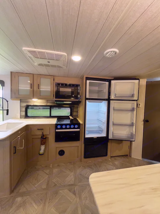 Well-equipped rv rental kitchen: sink, stove, microwave, large open fridge, and ample storage. Ready for your adventure!. Forest River Wildwood X-Lite Platinum 2024