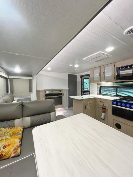 Modern RV rental interior showcasing a full kitchen, comfortable living area, and dining table.. Forest River Wildwood X-Lite Platinum 2024