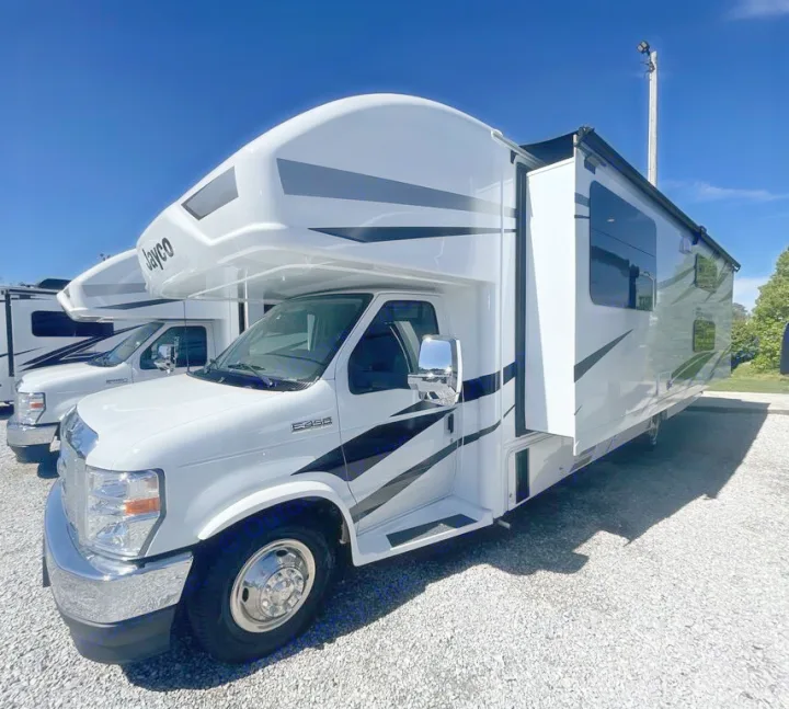 White Jayco Class C RV on gravel lot, with slide-out extended, ready for your next rv rental adventure under a clear sky.. Jayco Greyhawk 2026