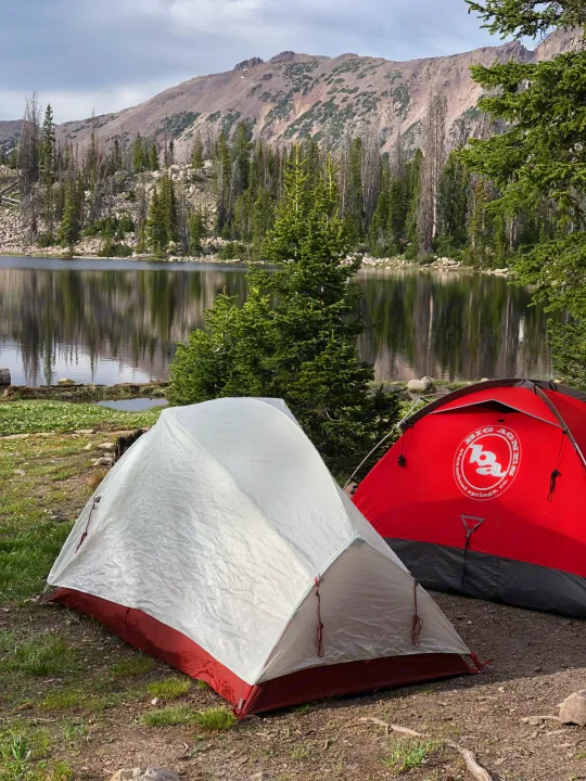 Two tents by a stunning mountain lake. Experience nature's raw beauty by primitive camping or with an RV rental for broader exploration.. Kia EV6 Wind All Wheel Drive 2022