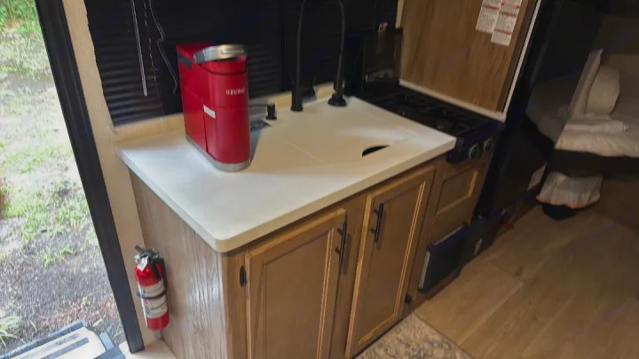This RV rental features a functional kitchen with a Keurig, covered sink, gas stove, and essential fire extinguisher.. Forest River Cherokee Wolf Pup 2025