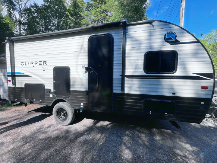 White & black Clipper travel trailer parked on gravel, ideal for an RV rental camping trip.. Clipper 4K 2023
