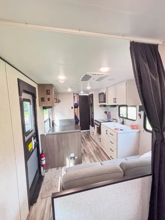 Spacious rv rental interior showing a kitchen, living area with grey couch, and dinette with wood-look flooring.. Jayco Jay Flight slx 260 bhw 2025