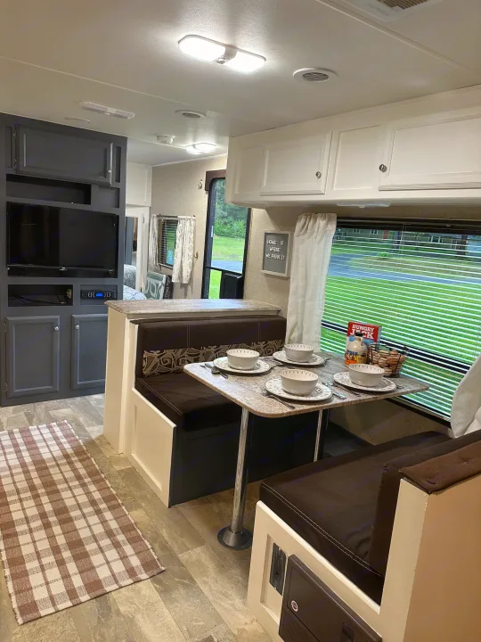 Cozy RV rental interior with dinette, table set for meals, and living area with TV. Perfect for family adventures.. Coachmen Apex LE 2017