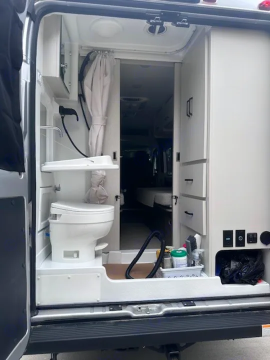 This compact RV rental interior features a clever wet bath with toilet & sink, plus integrated storage for mobile living convenience.. Thor Dazzle 2024