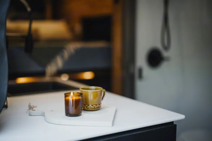 Cozy RV rental interior with a lit candle and a warm drink on a counter, perfect for relaxing moments.. Mercedes Sprinter 2023