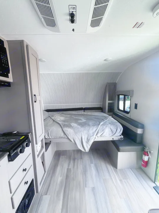 RV rental's inviting interior: features a comfy bed, compact kitchen, and dinette, all with light modern finishes.. Clipper 4K 2023
