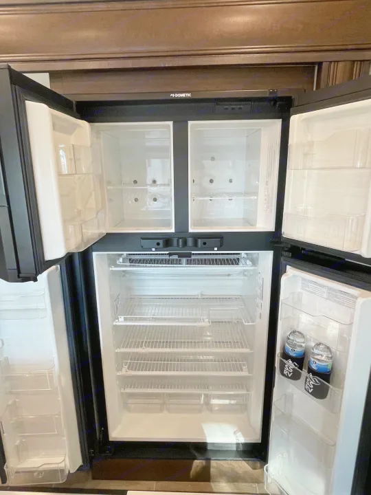 Open Dometic RV refrigerator, mostly empty with water bottles, ready for your rv rental.. Dutchmen 3602LFKB 2021