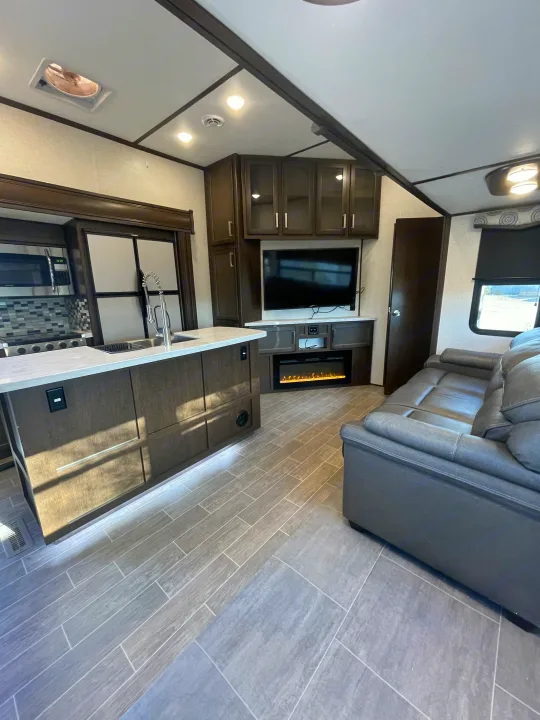 Modern RV rental: a spacious kitchen island, cozy fireplace, and comfy living area with sleek tile flooring.. Dutchmen 3602LFKB 2021
