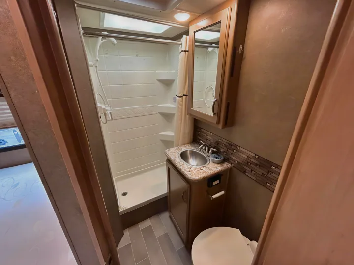 Compact RV rental bathroom with shower, toilet, and sink, designed for efficient use of space.. Thor Chateau 2019
