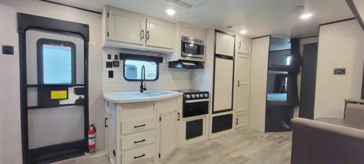RV rental interior featuring a modern kitchen with light cabinets, sink, stove, fridge, and a bunk bed area visible.. Jayco Jayco Rocky Mountain 2022