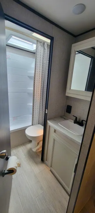 Compact RV rental bathroom features a shower, toilet, and vanity with sink, designed for efficient travel living.. Jayco Jayco Rocky Mountain 2022