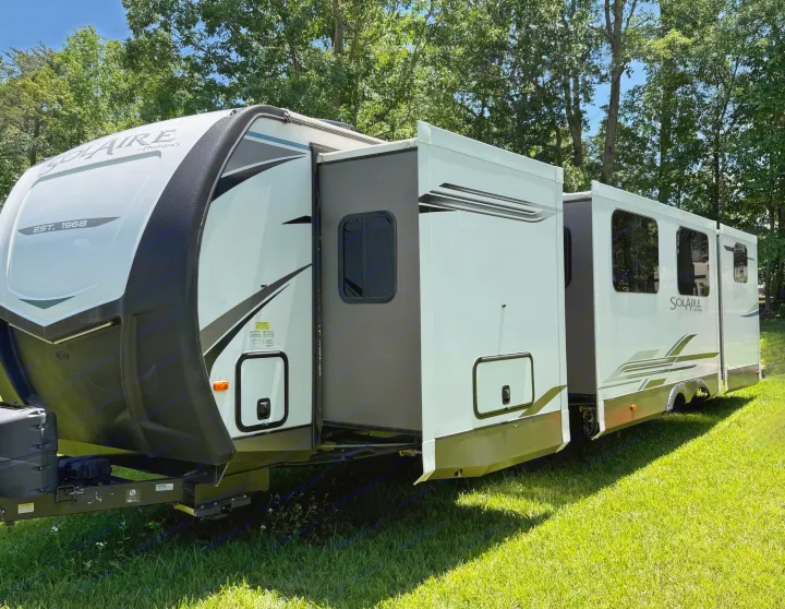 Extended slide-outs on a Solaire travel trailer (RV rental) parked on green grass, ready for outdoor adventures.. Palomino SolAire 320 TSBH 2022