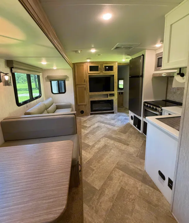 Inside this modern RV rental: a cozy dining area, living room with TV & fireplace, and a compact kitchen. Ready for adventures!. Palomino SolAire 320 TSBH 2022