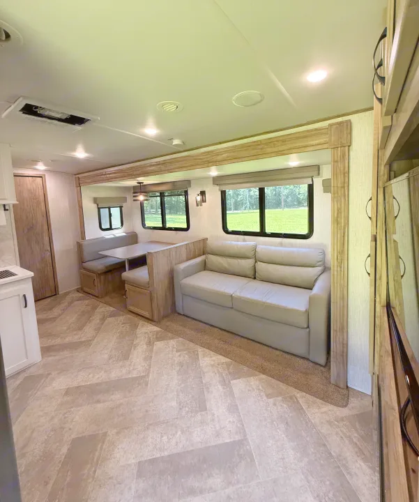 RV rental living space featuring a cozy sofa, dinette, and modern wood-look flooring.. Palomino SolAire 320 TSBH 2022