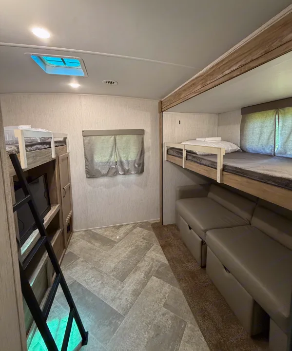 This RV rental bunkhouse features comfortable bunk beds, a skylight, and convertible dinette seating for family trips.. Palomino SolAire 320 TSBH 2022