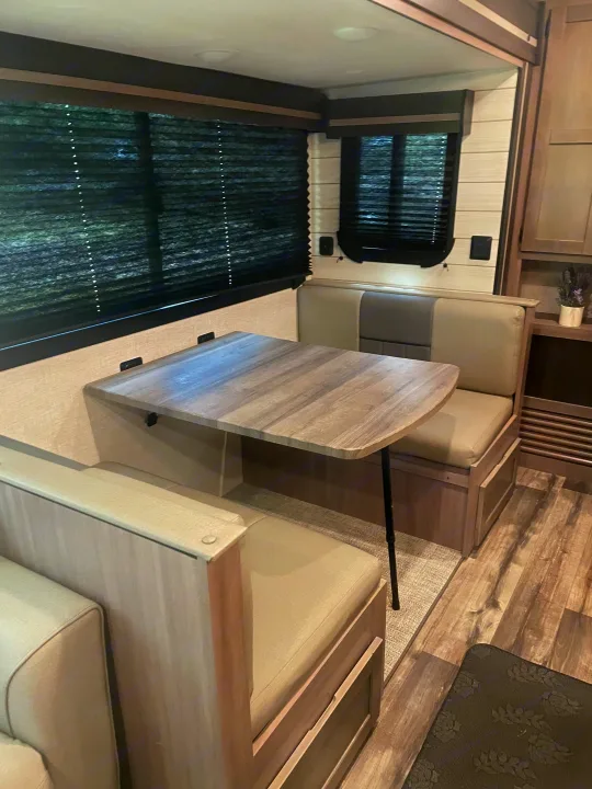Spacious RV rental dinette featuring a light wood table, comfortable cushioned seating, and large windows with blinds.. Crossroads RV Sunset Trail Super Lite 2023