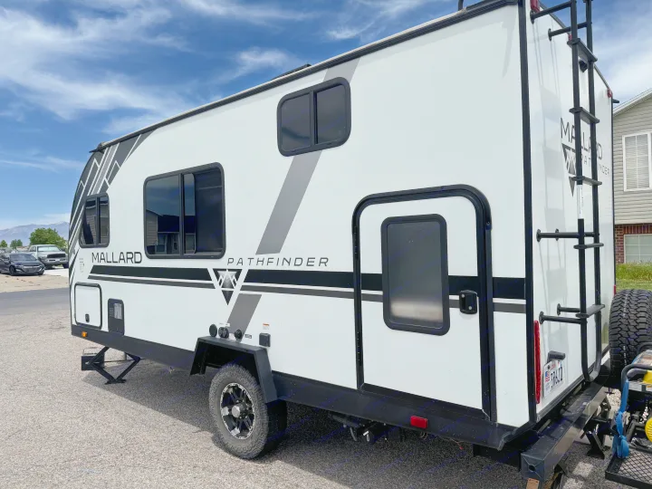 White Mallard Pathfinder travel trailer RV rental, parked with stabilizing jacks deployed under a blue sky.. Heartland RVs Mallard Pathfinder 2021