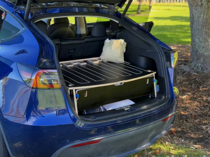 Blue Tesla Model Y's open trunk reveals a custom-built camping platform, functioning like a compact RV rental.. Telstar Model Y 2023