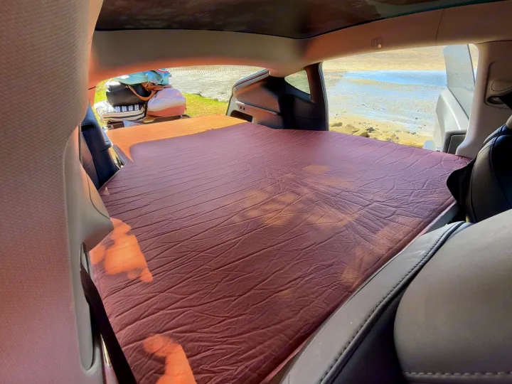 Cozy car bed setup for camping, overlooking a beach. A perfect road trip alternative to an RV rental.. Telstar Model Y 2023