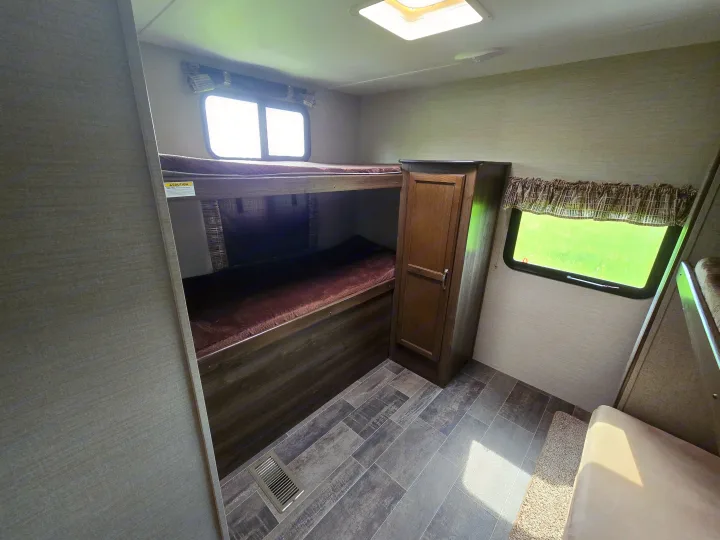RV rental interior features bunk beds, a wardrobe, and windows with green views. Great for family adventures.. Keystone RV Bullet Ultra Lite 2018