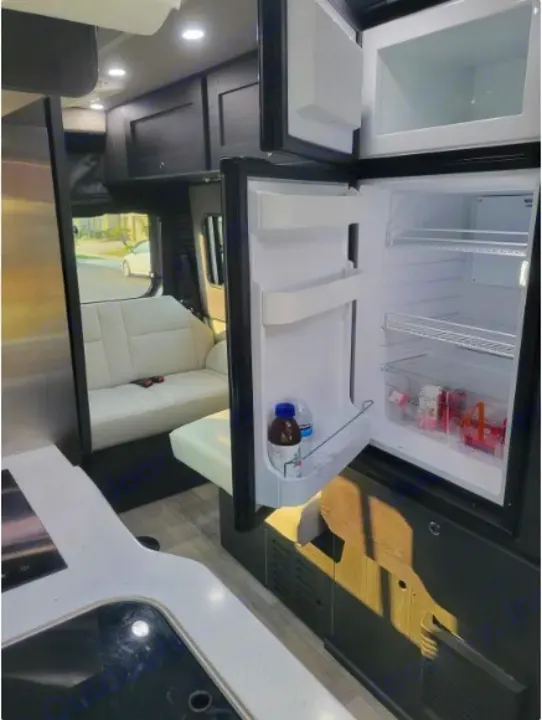 Inside a clean rv rental, showing a compact kitchen area with a fridge and comfortable seating.. Roadtrek Roadtrek Class B 2021