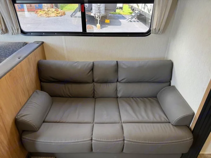 RV rental interior featuring a comfortable gray sofa and large window, perfect for relaxing on your journey.. Forest River Cherokee Grey Wolf 2023