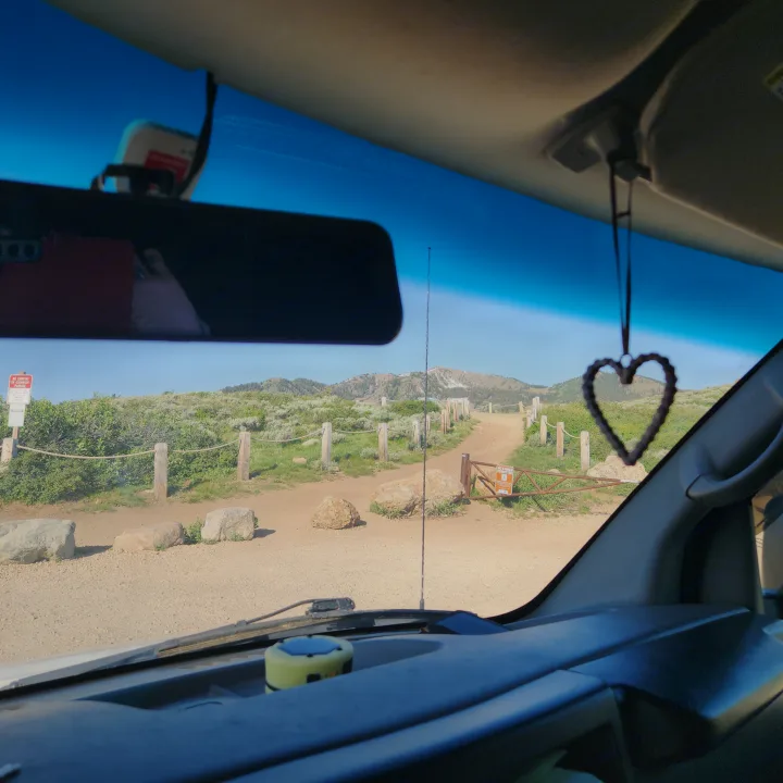 Inside an RV rental, looking out at a winding mountain road. A heart charm hangs, inviting scenic travel & adventure.. Chevrolet Express 1500 AWD 2014