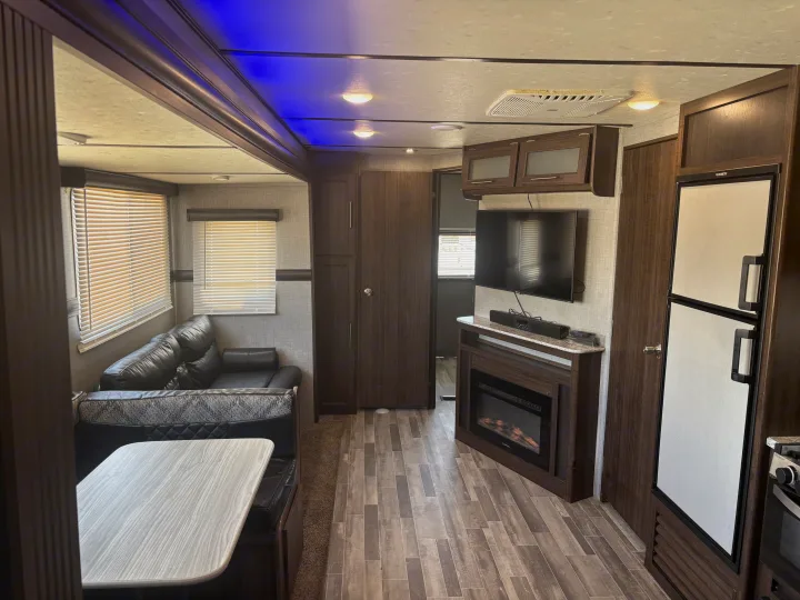 RV rental: Modern, spacious interior with a living area, dinette, TV, fireplace, and refrigerator, all wood-toned.. Crossroads RV Zinger 2020