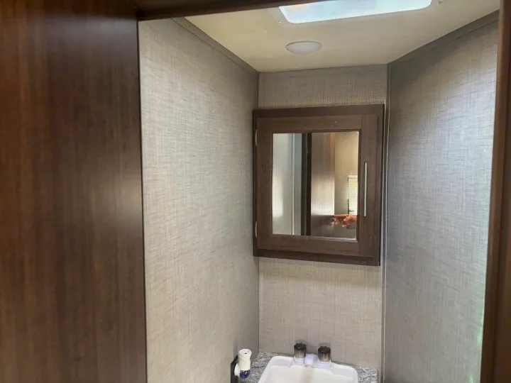 Inside an RV rental: a bright, compact bathroom featuring a sink, mirrored cabinet, and light-colored textured walls for travel comfort.. Crossroads RV Zinger 2020