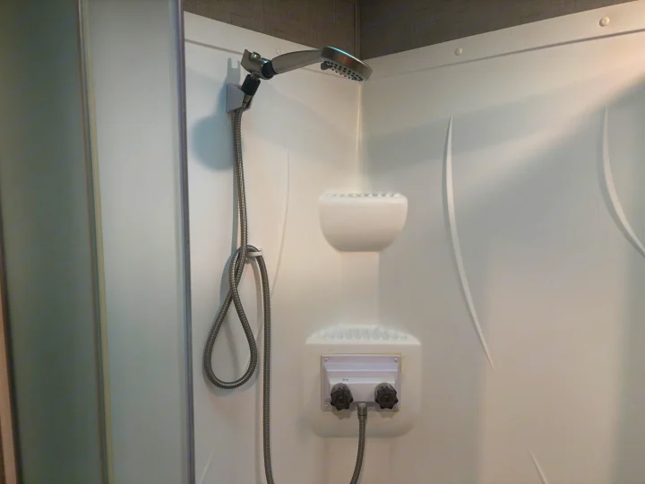 Clean white shower stall with a handheld showerhead and controls, typical for an RV rental bathroom.. Crossroads RV Zinger 2020