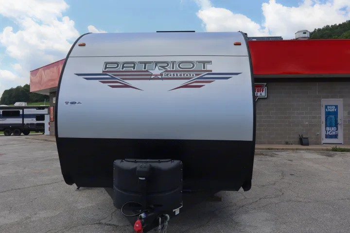 Front of a Patriot Edition travel trailer RV rental parked at a store, ready for adventure.. Forest River Patriot 274BRB 2022
