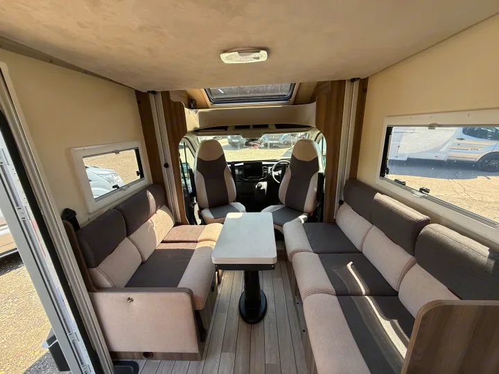 Spacious RV rental interior with comfortable dinette seating, table, and view into the driver's cabin. Ideal for campervan travel.. Rollerteam Kronos Compact 590 2026