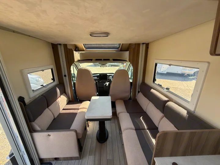 Spacious RV rental interior: lounge area with comfy bench seating, central table, and front cabin view.. Rollerteam Kronos Compact 590 2026