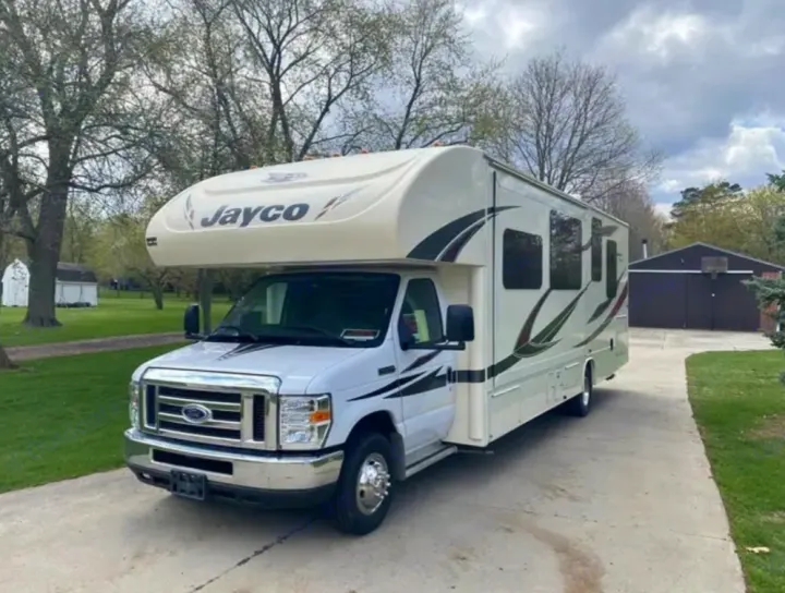 White Jayco Class C RV for rental, parked on a driveway. Ready for your next road trip adventure!. Jayco Redhawk 2017