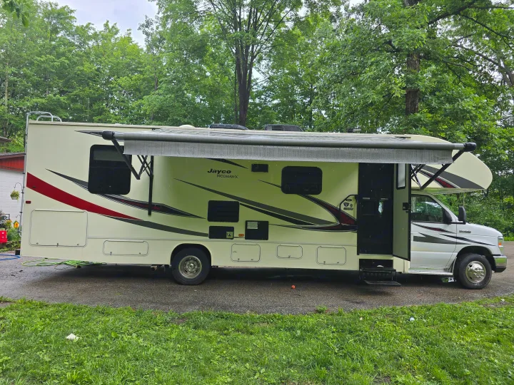 A beige and white Jayco Redhawk Class C rv rental, with awning extended, is parked on a gravel drive.. Jayco Redhawk 2017