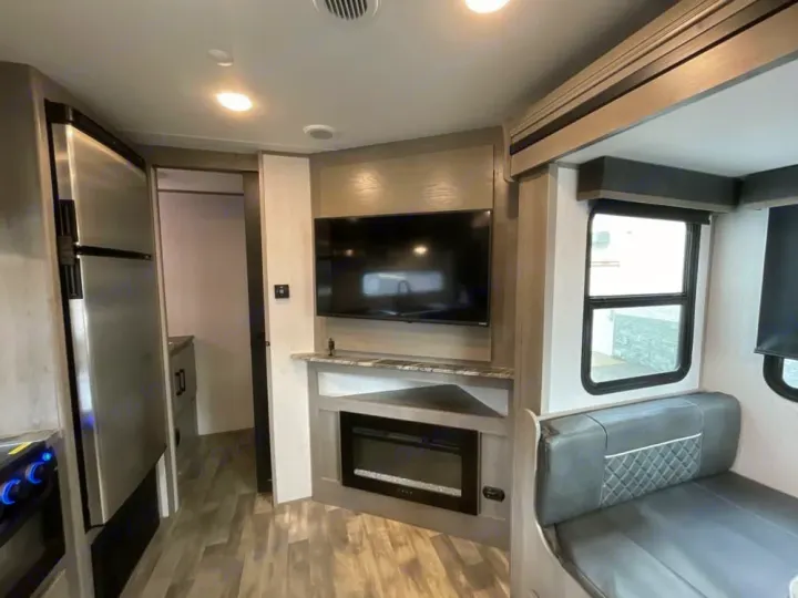 Inside a modern rv rental: TV, fireplace, dinette, and kitchen appliances. A compact, cozy, and well-equipped living space.. Dutchmen Kodiak Ultra Lite 2022